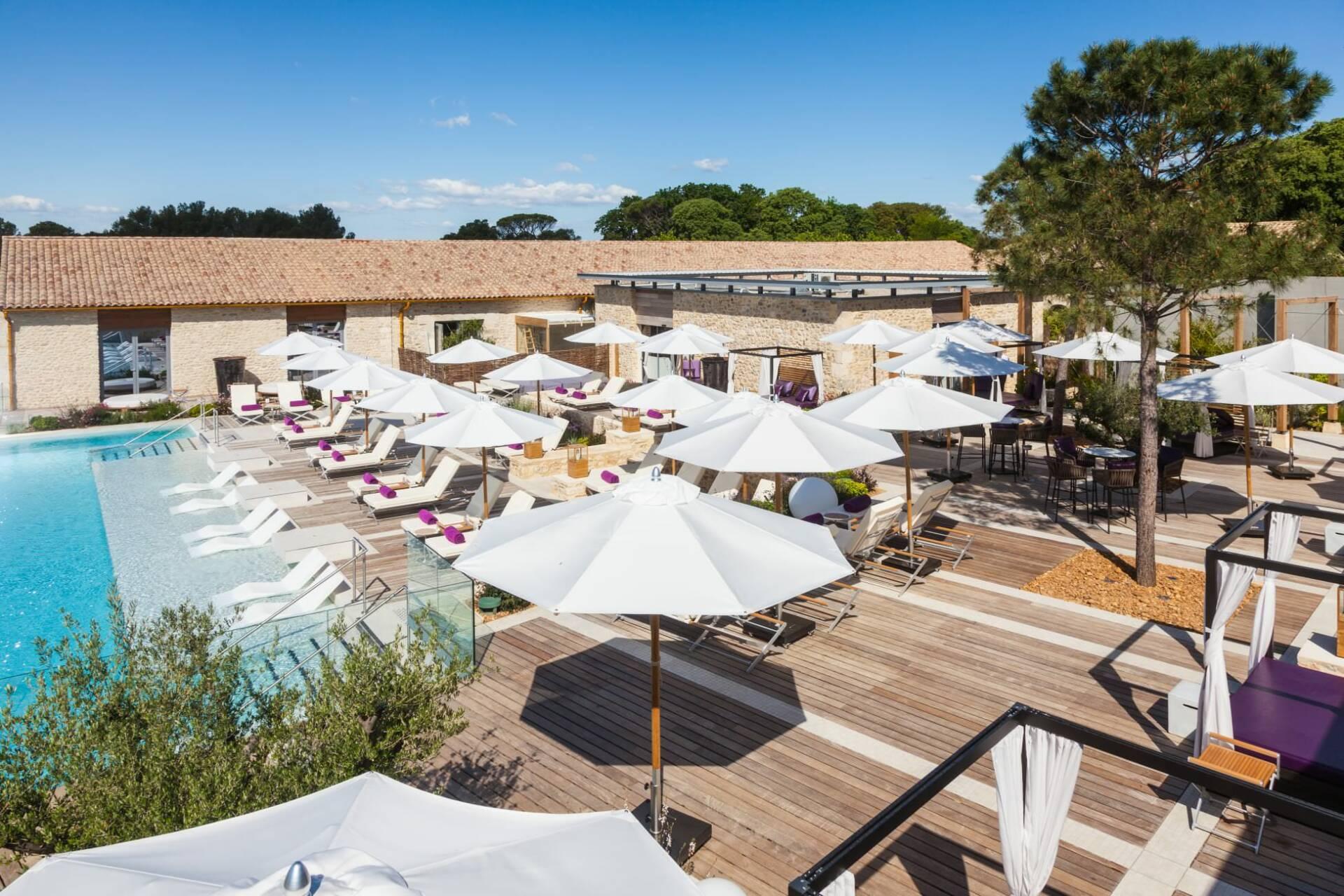 Grande plage de piscine en bois avec transats et parasols blancs