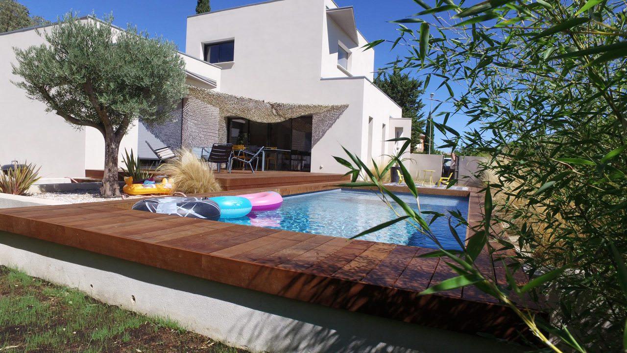 Lames de bois aux teintes chaudes entourant une piscine dans un jardin